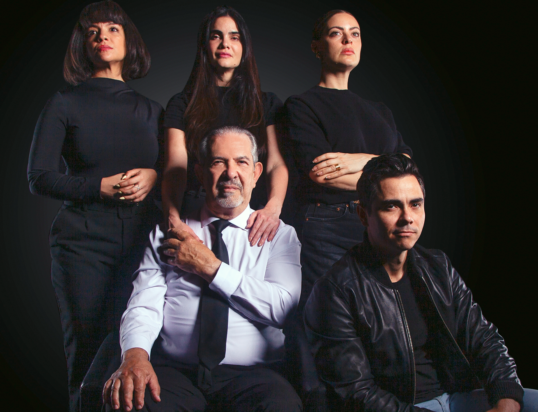 Thumbnail of http://A%20group%20of%20five%20people%20poses%20confidently%20against%20a%20dark%20background.%20Three%20women%20and%20two%20men%20wear%20black%20and%20white%20outfits,%20conveying%20a%20serious%20tone.