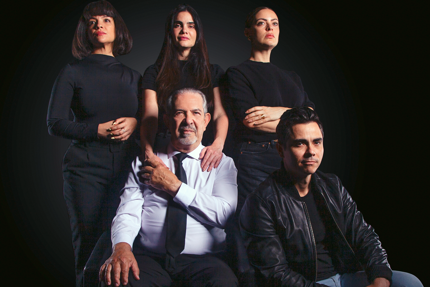 A group of five people poses confidently against a dark background. Three women and two men wear black and white outfits, conveying a serious tone.